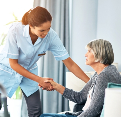 A caregiver from Assured Home Nursing sitting and talking with a smiling senior woman in her Bloomfield Hills living room